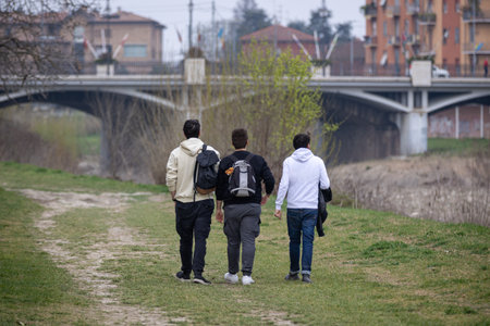 Three Boys Walking on the Lawn along the Banks of a Dried up River and a Bridge in the Background.の写真素材