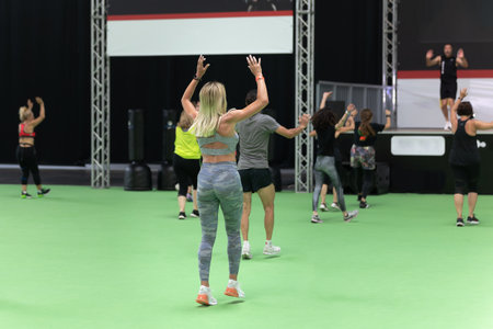 Fitness Workout in Gym: Girls doing Exercises in Class with Music and Teacher on Stage.