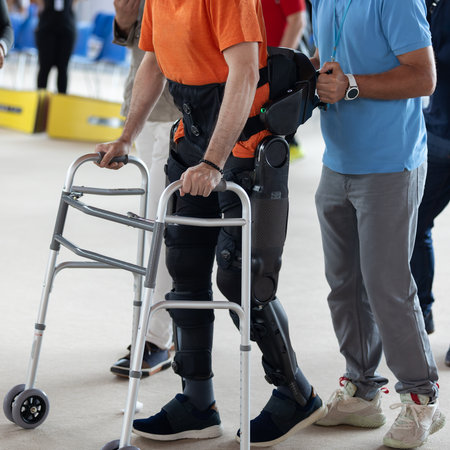 Boy with Mobility Problems in Lower Limbs in Upright Posture Walking Thanks to a Mechanical...