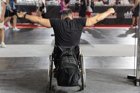 Man Sitting in a Wheelchair with a Backpack attached doing Arm and Shoulder exercises with Gym...