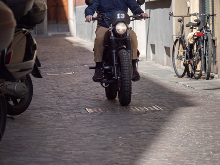 Detail of a Black Motorcycle Seen from the Frontside on a City Road with Cobblestone in Italy.