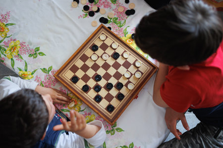 View from Above of a Checkers Game Board and two Children playing Checkers.