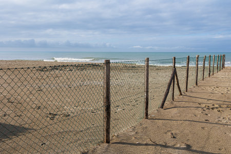 Deserted and Desolate Beach in Winter Time - Wooden Poles with Dividing Net.の写真素材
