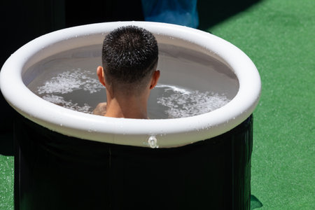 Boy immersing himself in little Circular Pool Filled with Water and Ice: Ice Baths and Wellness.