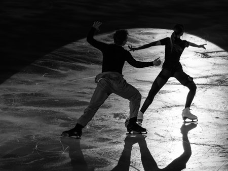 Backlight of a Professional Skating Athlete Couple and their shadow reflected on the Ice Rink during the Artistic and Technical performance.の写真素材