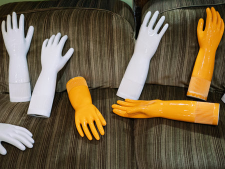 Collection of Ceramic Glove-Like Art Pieces in White and Orange Tones Laying on Sofa.の写真素材