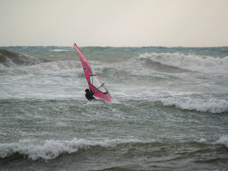Water Sport Activity - Windsurfer Riding a Wave in Rough Sea on a Windy Day.の写真素材