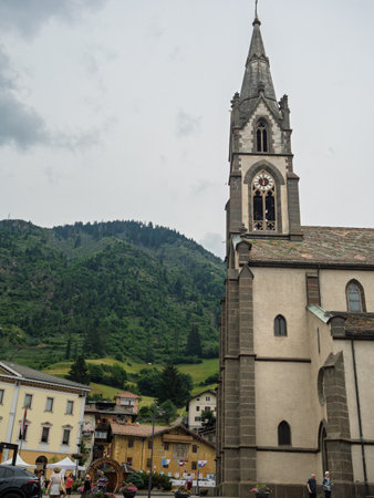 Predazzo Village With A Church Spire and Colorful Flowers On A Main Street - Italy.の写真素材