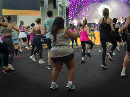 Fitness Workout in Gym: People doing Exercises in Class with Music and Teacher on Stage.