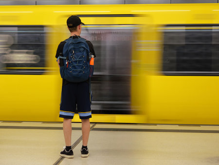 Yellow Subway Vehicle Speeding Past Station Platform and Boy with Cap Waiting For Train.の写真素材