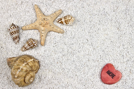 a seastar and several shells in white sand with a heartの写真素材