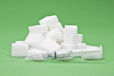 sugar cubes with an syringe as a symbol for diabetes