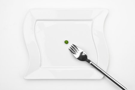 one pea on a white plate with a forkの写真素材