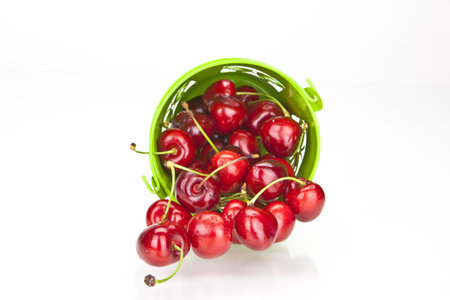 fresh red cherries in a green bowl on white backgroundの写真素材
