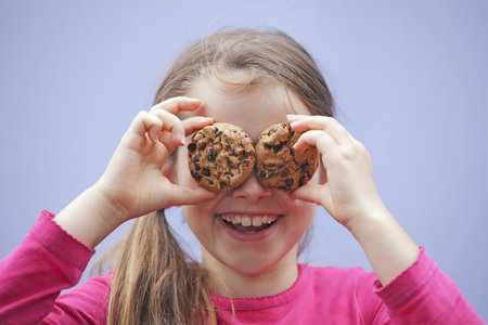 a seven-year-old girl eating chocolate cookiesの写真素材