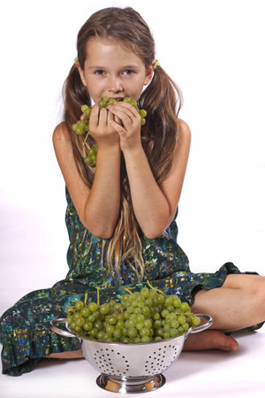 eight year old girl eating freshly picked grapes from the gardenの写真素材