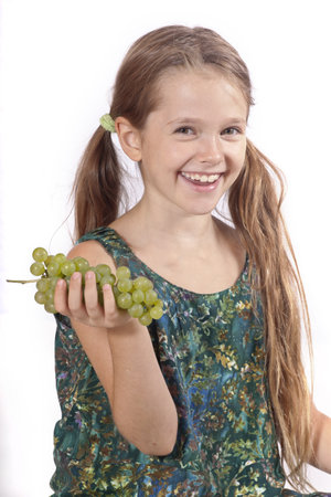 eight year old girl eating freshly picked grapes from the gardenの写真素材