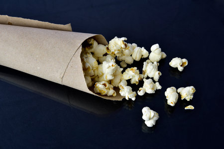popcorn falling from paper packaging with wood background.の写真素材