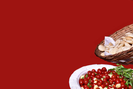 Delicious caprese salad with ripe cherry tomatoes and mini mozzarella cheese balls with fresh basil leaves. Italian healthy food concept with copy space. View from above.の写真素材