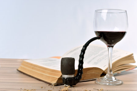 .pipe, red wine, old book on the table