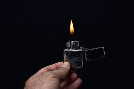 holding lighter lit on black backgroundの写真素材
