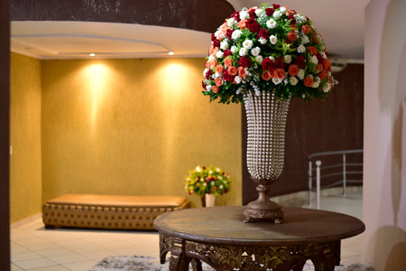 A luxurious bouquet of fresh flowers in a crystal vase on the table with plates, cutlery and an elegant portion in the restaurant with blur in the background.の写真素材