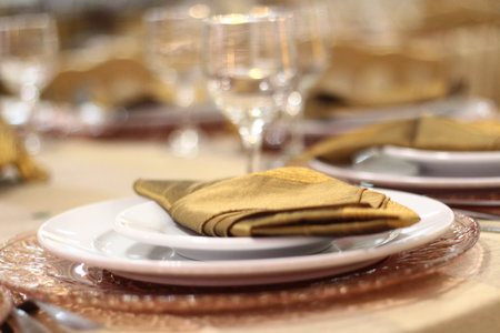 luxury dining table, cutlery, plates, cups, red napkins with blurred background,.の写真素材