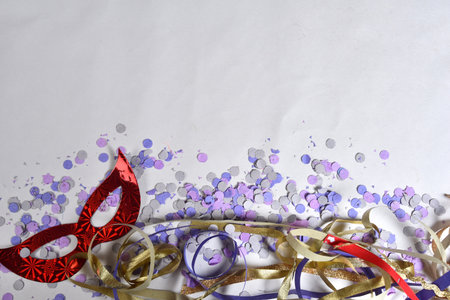 red carnival costume mask in colorful confetti and streamers on pink background with space for text,の写真素材