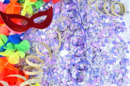 red carnival costume mask in colorful confetti and streamers on pink background with space for text,の写真素材
