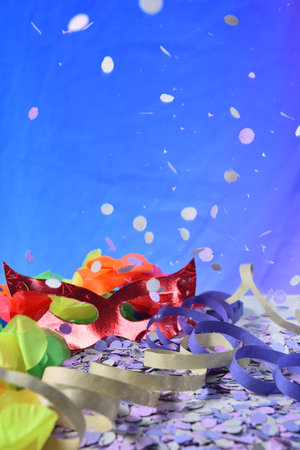 red carnival costume mask in colorful confetti and streamers on pink background with space for text,の写真素材