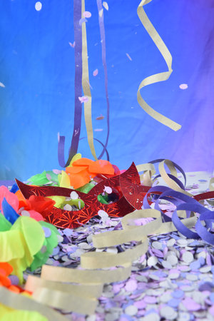 red carnival costume mask in colorful confetti and streamers on pink background with space for text,の写真素材