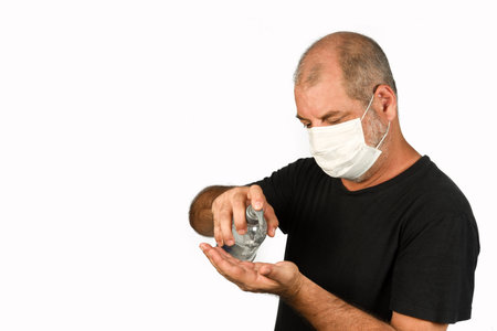Retrato de um homem, em uma mÃ¡scara mÃ©dica usando gel de Ã¡lcool. Um conceito do perigo do coronavÃ­rus COVID-19 para idosos. sobre fundo branco, com espaÃ§o para textoの写真素材
