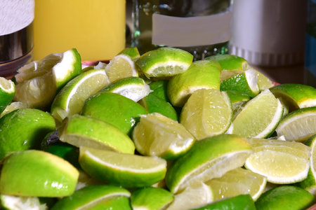 lemons cut into pieces in a copper bowl with some bottles out of focus in the background.