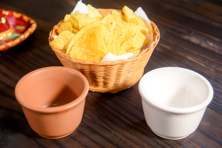 Delicious bowl of traditional Mexican Guacamole, nachos and guacamole ingredients: Avocado, onion, cilantro, hot pepper tomatoes and lime.Top view, flat lay. Fresh, raw, vegetarian dish, copy spaceの写真素材