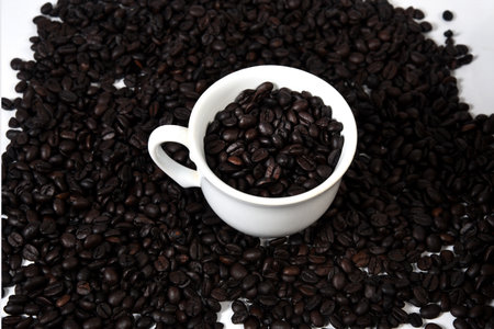white cup with roasted coffee beans isolated with copy space