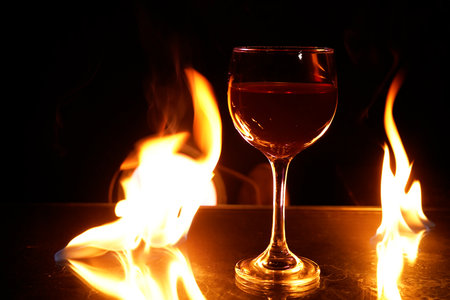 glass of red wine on the table with fire in the background fine art