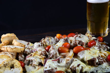 meat roasted on a barbecue plate with melted cheese tomato onion and breadの写真素材