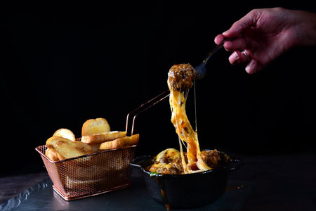 creamy rice with meat, melted cheese, meatballs served in an iron pan with breadの写真素材