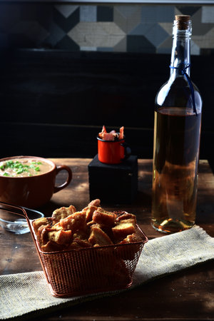 pork rinds (crackling) fried in ceramic bowl on rustic wooden table in restaurant. typical dish of...