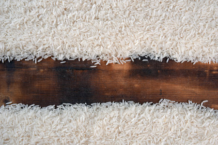 white rice natural long grain rice on wooden table use texture backgroundの写真素材