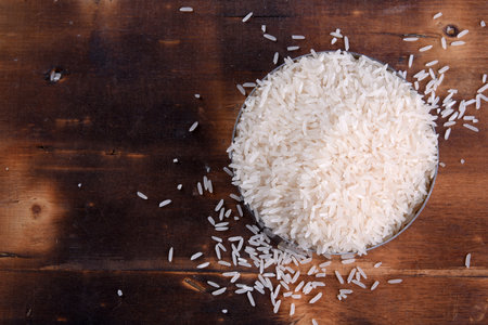white rice natural long rice grain uncooked healthy food wooden table use texture backgroundの写真素材