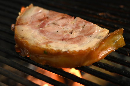 bacon pork rinds roasting on a charcoal barbecue lit wood with fire for roasting pork pancetta on the grill tasteの写真素材
