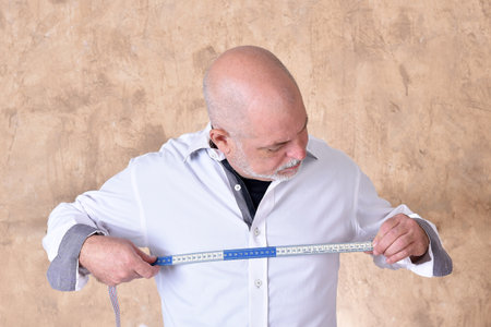 portrait of charming man taking measurements in white shirt with gray beard modelの写真素材