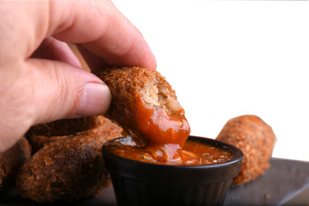 fried cod dumpling with herb sauce on the table in the dark background with blurred mug of draft beer.の写真素材
