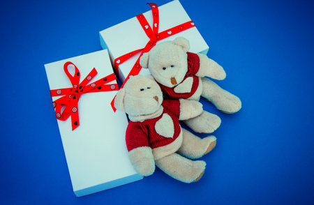 Two white gift boxes and two bears on blue backgroundの写真素材
