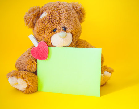 Envelope with heart and a toy bear on yellow backgroundの写真素材