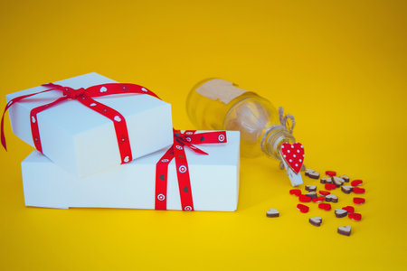 Gift boxes, hearts and bottle on yellow backgroundの写真素材