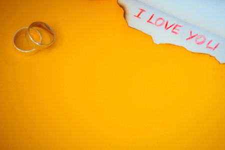 Love message and rings on yellow backgroundの写真素材