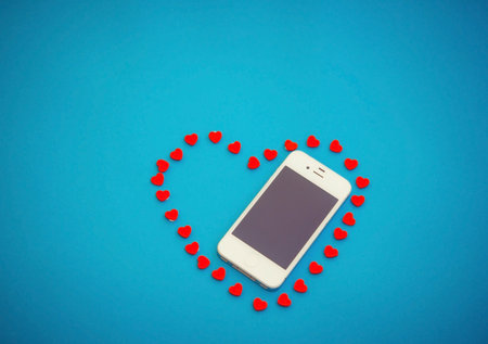 White phone with red hearts on blue backgroundの写真素材