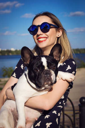 Beautiful young girl on the beach playing with french bulldogの写真素材